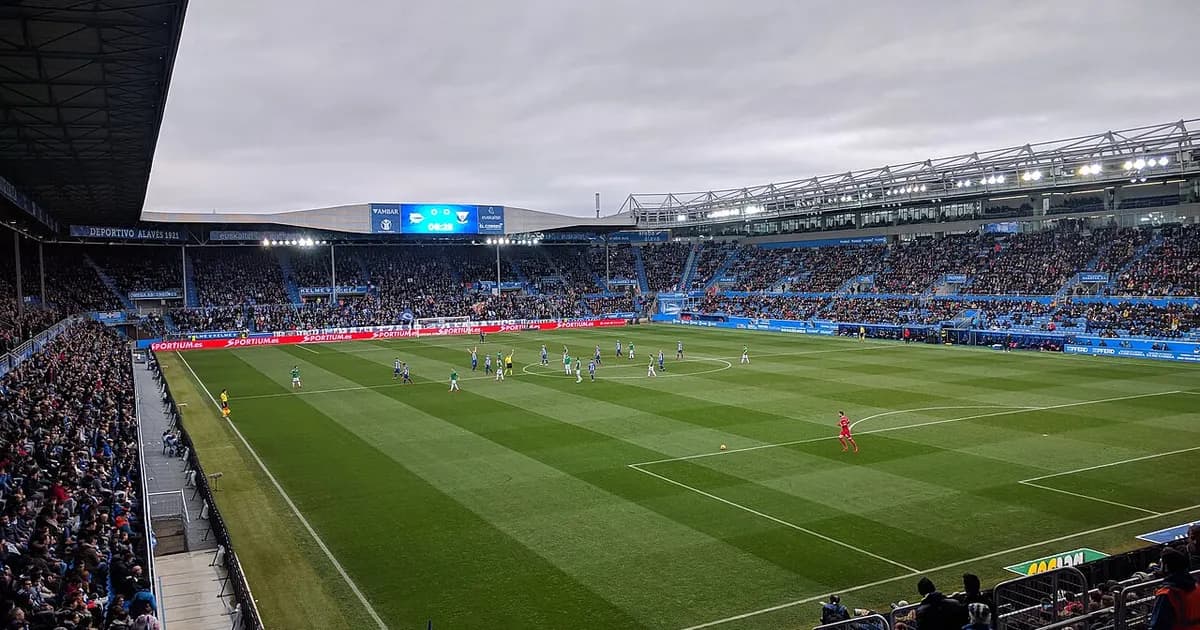 General view of a football stadium's pitch and stands before kickoff, under stadium floodlights