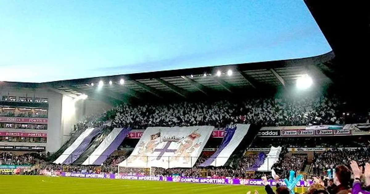 General view of a football stadium's pitch and stands before kickoff, with floodlights on and empty seats ahead of a European night match.