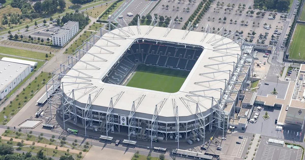 General view of an empty football stadium with green pitch and stands before kickoff